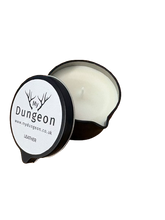 Load image into Gallery viewer, An open round tin candle with white wax and a black rim, shown on a plain white background. The lid has a white label with the brand name 'My Dungeon' and scent text 'LEATHER'.
